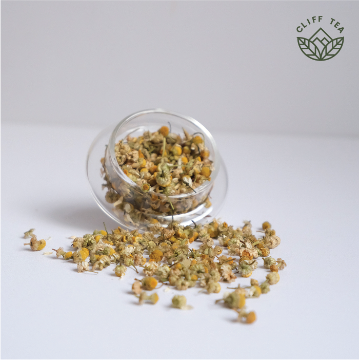 Chamomile flowers and tea cup on wooden surface