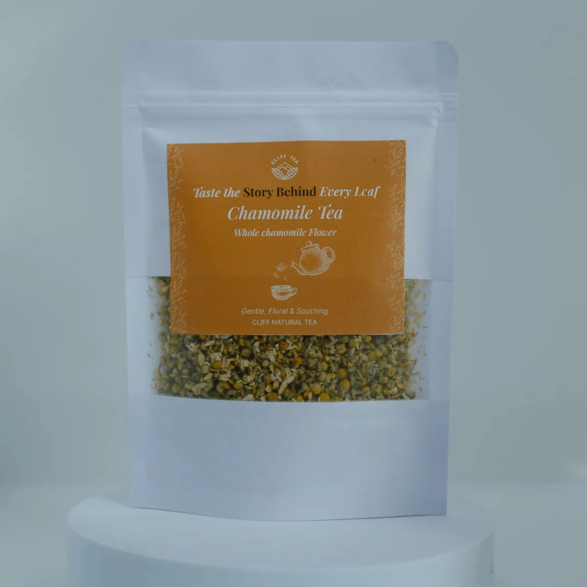 Whole dried chamomile flowers beside a cup of golden chamomile tea
