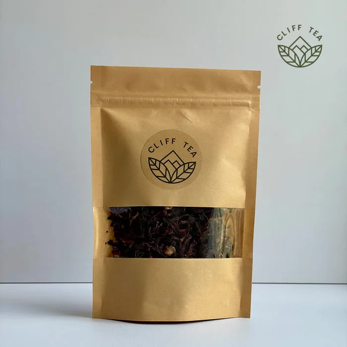 Whole dried hibiscus flowers next to a cup of deep red hibiscus tea